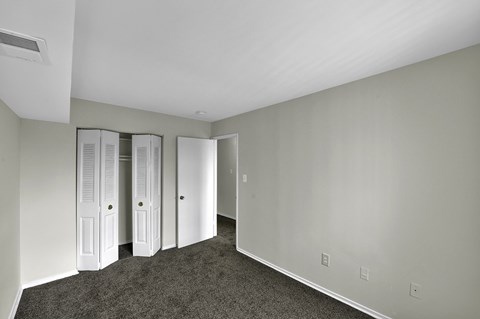 a bedroom with white walls and two closet doors